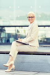 Image showing young smiling businesswoman with notepad outdoors