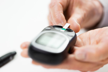 Image showing senior woman with glucometer checking blood sugar