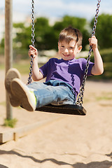 Image showing happy little boy swinging on swing at playground