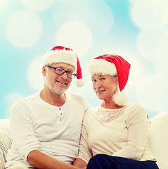 Image showing happy senior couple in santa helper hats