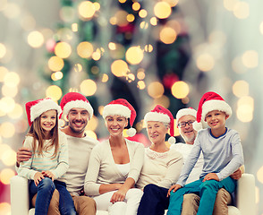 Image showing happy family in santa helper hats sitting on couch