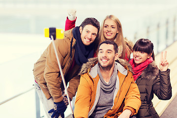 Image showing happy friends with smartphone on skating rink