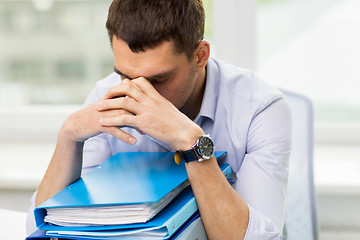 Image showing sad businessman with stack of folders at office