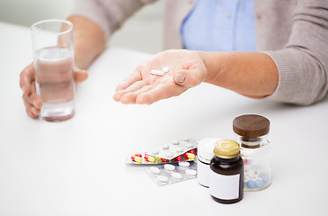 Image showing close up of senior woman with pills and water 