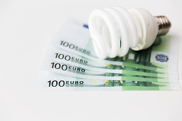 Image showing close up of euro money and light bulb on table