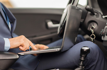 Image showing close up of young man with laptop driving car