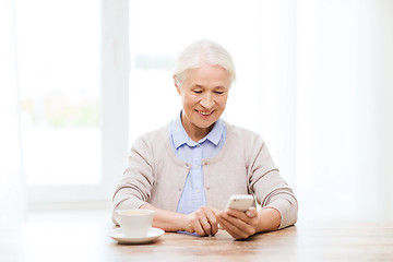 Image showing senior woman with smartphone texting at home