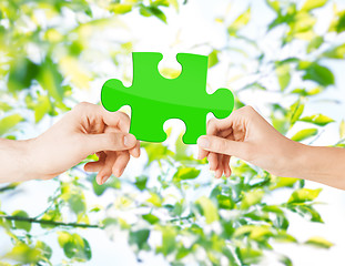Image showing hands with green puzzle over natural background