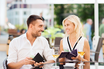 Image showing happy couple with wallet paying bill at restaurant