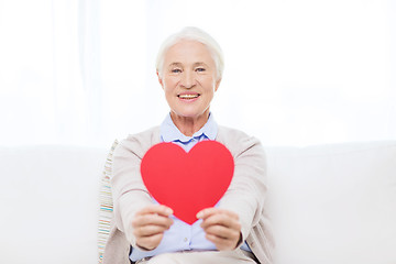 Image showing happy smiling senior woman with red heart at home