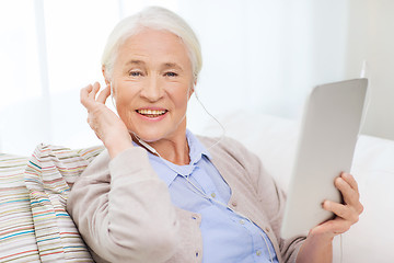 Image showing senior woman with tablet pc and earphones at home