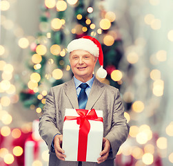 Image showing smiling man in suit and santa helper hat with gift