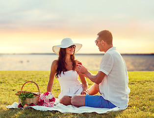 Image showing smiling couple with small red gift box on picnic