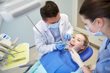 Image showing male dentist treating female patient teeth