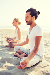 Image showing smiling couple making yoga exercises outdoors