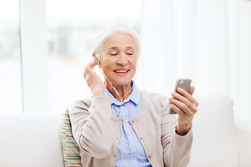 Image showing senior woman with smartphone and earphones at home