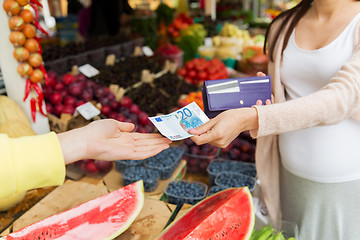 Image showing pregnant woman with wallet buying food at market