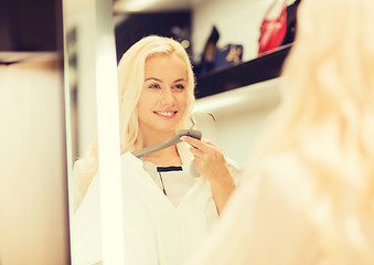 Image showing happy young woman choosing clothes in mall