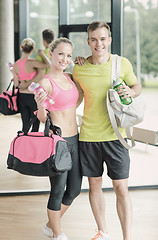 Image showing smiling couple with water bottles in gym