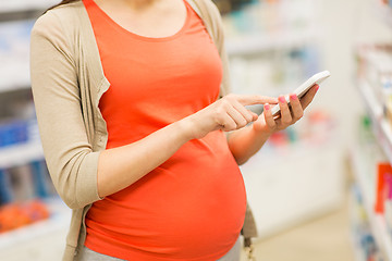 Image showing pregnant woman with smartphone at pharmacy