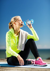 Image showing woman drinking water after doing sports outdoors