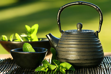 Image showing Black asian teapot with mint tea