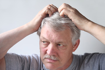 Image showing Senior scratches his head.