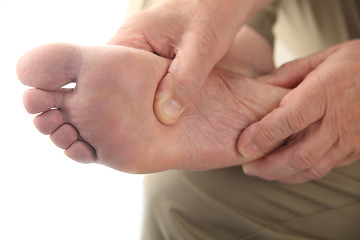 Image showing a man checks his aching foot