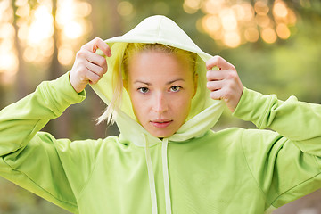 Image showing Confident sporty woman wearing fashionable green hoodie. 