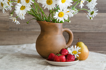 Image showing Bouquet of daisies in a clay jug and strawberries with pears. Co