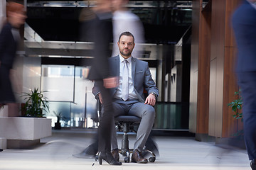 Image showing business man sitting in office chair, people group  passing by