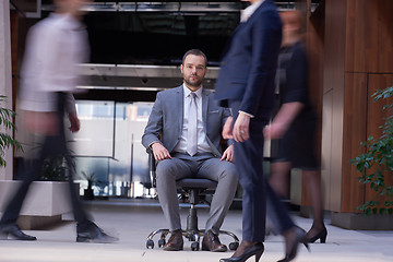 Image showing business man sitting in office chair, people group  passing by