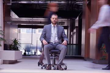 Image showing business man sitting in office chair, people group  passing by