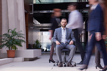 Image showing business man sitting in office chair, people group  passing by