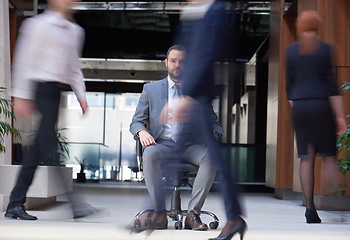 Image showing business man sitting in office chair, people group  passing by