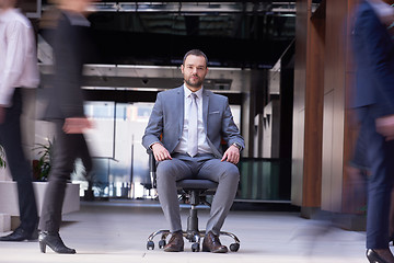 Image showing business man sitting in office chair, people group  passing by