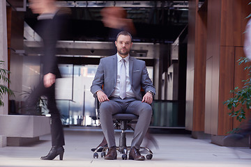 Image showing business man sitting in office chair, people group  passing by