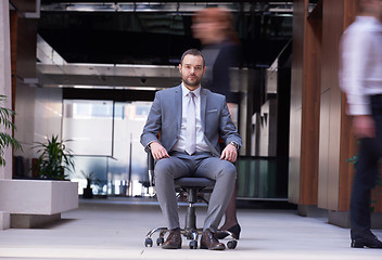 Image showing business man sitting in office chair, people group  passing by