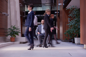 Image showing business man sitting in office chair, people group  passing by