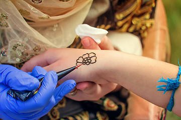 Image showing A tattoo artist applying his craft onto the hand of a female