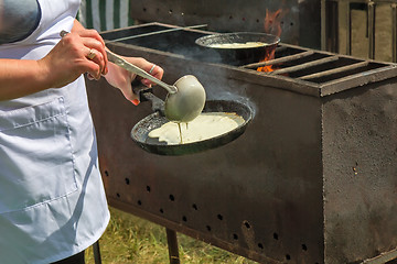 Image showing Woman frying pan pancakes on the grill.