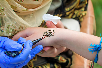 Image showing A tattoo artist applying his craft onto the hand of a female