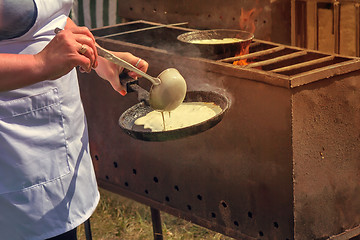 Image showing Woman frying pan pancakes on the grill.