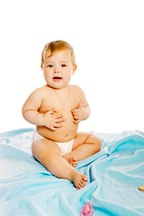 Image showing baby in diaper sitting on a blue blanket. Isolated