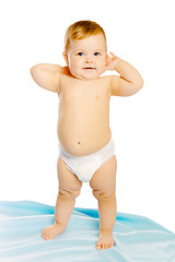 Image showing baby in diaper standing on a blue blanket. Studio. Isolated