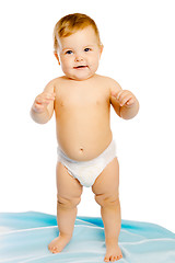 Image showing baby in diaper standing on a blue blanket. Studio. Isolated