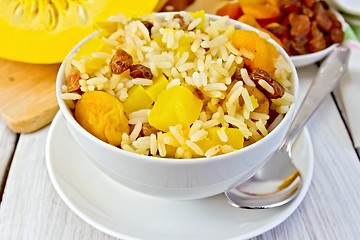 Image showing Pilaf fruit with pumpkin in bowl and spoon on board