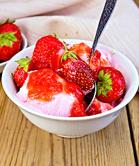 Image showing Ice cream strawberry in white bowl with spoon on board