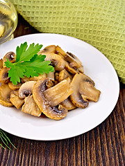 Image showing Champignons fried in plate with oil on light board