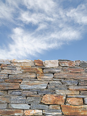 Image showing Vertical background with rough stone wall and blue cloudy sky